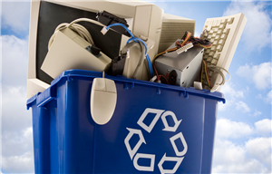 A recycling bin overflowing with electronics, such as computer monitor, keyboard, and mouse.