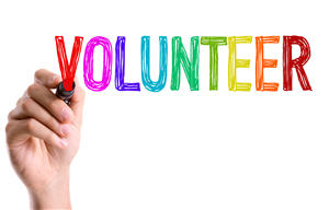 A hand holding a marker writing the word Volunteer