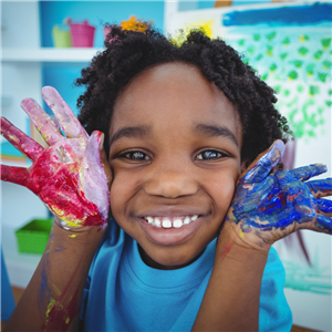 Young girl smiling big holding hands by her face and covered in paint