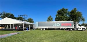 Semi Truck on right side of photo with CSO POPS printed on the trailer and white tent with stage and scaffolding on left side of photo
