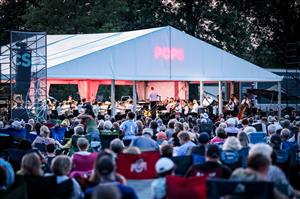 White tent with the word POPS in red print, and an audience in the foreground