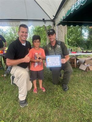 A sheriffs deputy, a boy holding a trophy, and a wildlife officer
